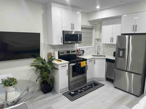 a kitchen with white cabinets and stainless steel appliances at Award winning boho paradise sunlit modern suite in Calgary