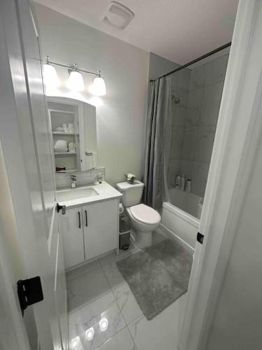 a white bathroom with a toilet and a sink at Award winning boho paradise sunlit modern suite in Calgary