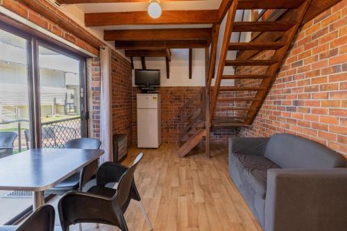 a living room with a brick wall and a table and chairs at Walpole Rest Point Caravan Park in Walpole
