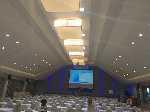 a large room with a stage and a projection screen at Buritel Hotel in Buriram