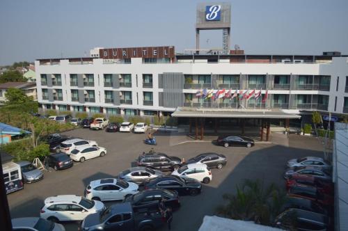a parking lot with cars parked in front of a building at Buritel Hotel in Buriram