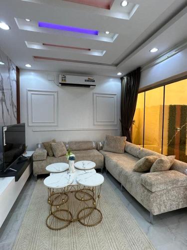 een woonkamer met een bank en 2 tafels bij شاليه in Al Maʼish