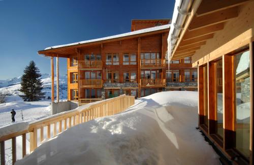 a building in the snow with a skier in front of it at Résidence Odalys Edenarc in Arc 1800