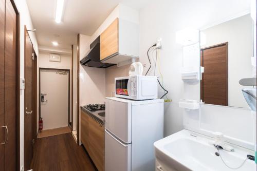 a small kitchen with a white refrigerator and a microwave at KINTARO Hotel Okinawa Naha in Naha