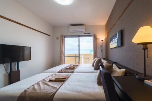 那覇市にあるKINTARO Hotel Okinawa Nahaの大きな窓付きの大きなベッドが備わるホテルルームです。