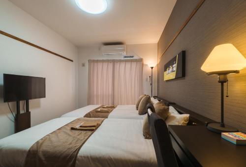 a hotel room with a large bed and a desk at KINTARO Hotel Okinawa Naha in Naha