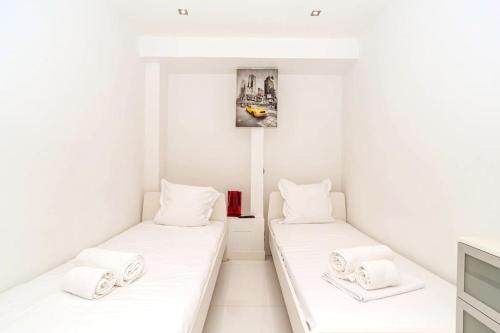 deux lits dans une chambre aux murs blancs dans l'établissement Croisette 1 mn 2 BR w/ terrace Olam Properties, à Cannes