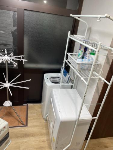 a laundry room with a washing machine and a shelf at 11月フルリフォーム 12月オープン恐竜一色ゲストハウスDinosaur Guesthouse in Katsuyama