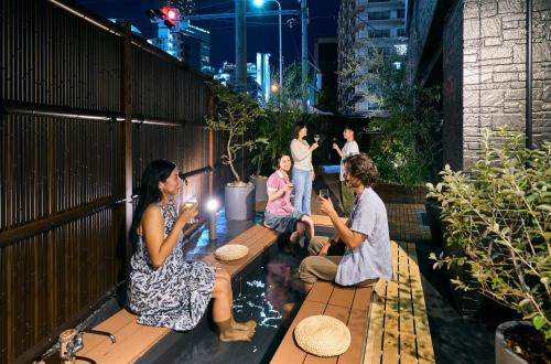 un groupe de personnes assises sur un banc dans un jardin dans l'établissement COGO TENNOJI, à Osaka