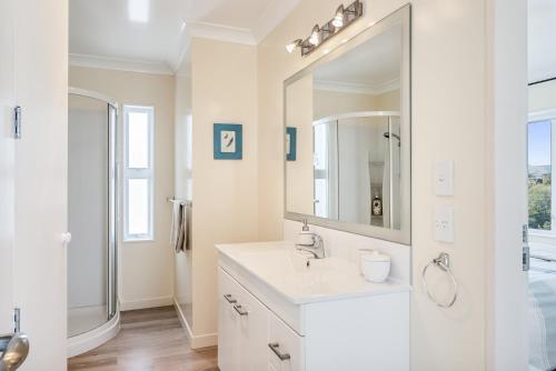 a white bathroom with a sink and a mirror at Otaki Beach Haven - Otaki Beach Holiday Unit in Otaki