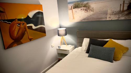 ein Schlafzimmer mit einem Bett und einem Gemälde an der Wand in der Unterkunft The Ocean House - Budgewoi in Budgewoi