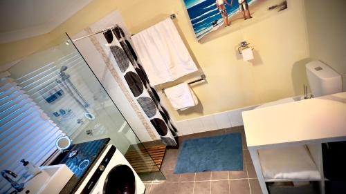 a bathroom with a glass shower and a sink at The Ocean Street House in Budgewoi