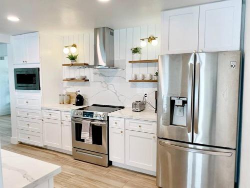 a kitchen with white cabinets and a stainless steel refrigerator at Newly remodeled beauty in Phoenix in Phoenix