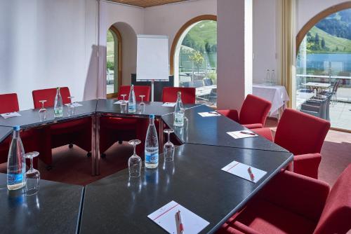 a meeting room with a table and red chairs at Hostellerie am Schwarzsee in Bad-Schwarzsee