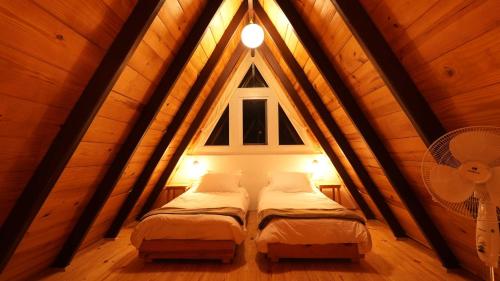 2 camas num quarto no sótão com uma janela em amã Stays & Trails Godhuli Cottages Naukuchiatal em Nainital