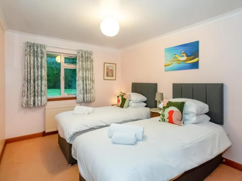 dwa łóżka w pokoju z dwoma oknami w obiekcie Smiddy Cottage w mieście Alyth