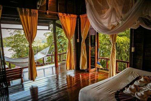 a room with two beds and a hammock on a balcony at Hillhouse - Koh Yao Noi in Ko Yao Noi