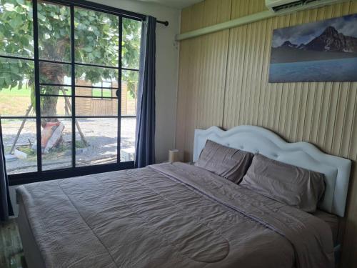 um quarto com uma cama grande e uma janela grande em November Garden ชัยนาท 