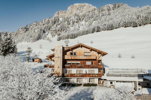 a building in the snow with a mountain in the background at Residence Costa Burjada in Colfosco