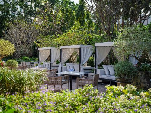 a patio with tables and chairs in a garden at InterContinental Chiang Mai The Mae Ping in Chiang Mai