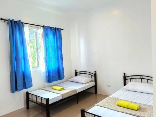 two beds in a room with blue curtains at Divers Lodge Plumeria in Moalboal