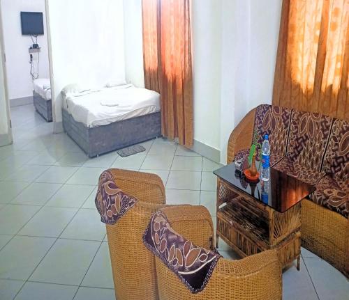Zimmer mit 2 Stühlen, einem Tisch und einem Bett in der Unterkunft Mountain Green Club and Resort in Shiliguri