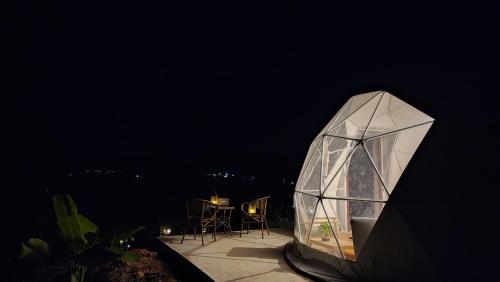 a glass house with a table and chairs on a balcony at Geffen Khaokho in Khao Kho