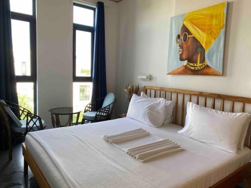 a bedroom with a white bed with a painting on the wall at Stylish flat with balcony & pool at Paje Beach in Paje
