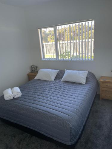 a bed with two pillows in a bedroom with a window at Wander Inn in Kaitaia