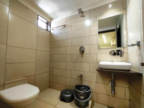 La salle de bains est pourvue de toilettes, d'un lavabo et d'un miroir. dans l'établissement Hotel Kinara, à Ahmedabad