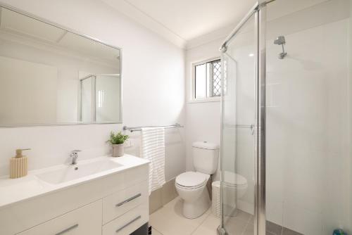 a white bathroom with a toilet and a shower at New Listing, Wi-Fi and Laundry in Brisbane