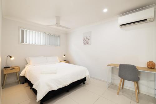 a white bedroom with a bed and a desk at New Listing, Wi-Fi and Laundry in Brisbane