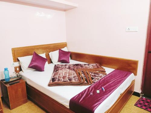 Bett in einem Zimmer mit lila Kissen in der Unterkunft SNR Cottage & Rooms in Udagamandalam