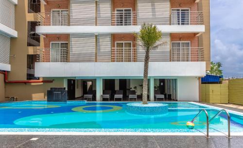 a swimming pool with a palm tree in front of a building at The Piku's Inn in Digha