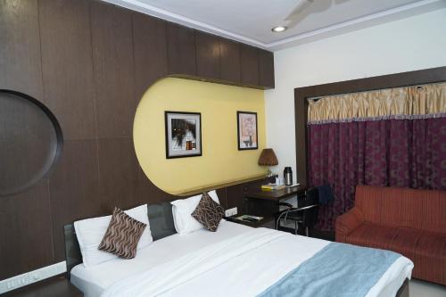 a hotel room with a bed and a red couch at Marshall The Grand Hotel in Ahmedabad