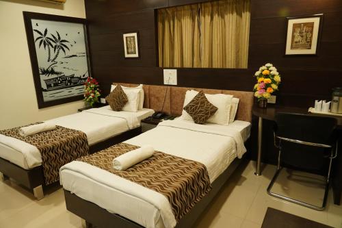 a hotel room with three beds and a desk at Marshall The Grand Hotel in Ahmedabad