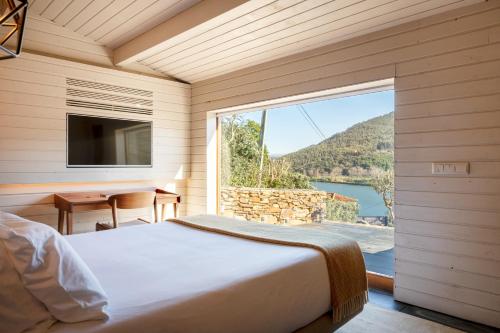 a bedroom with a bed and a large window at DOURWIN - Riverside Suites - Adults Only in Penafiel