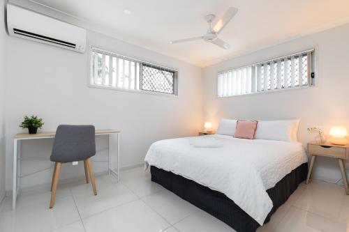 a bedroom with a bed and a desk and two windows at Super Host and New Listing in Brisbane