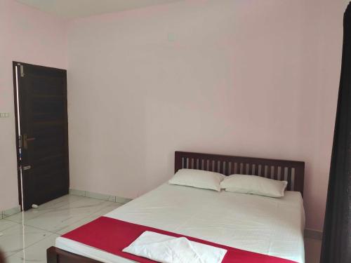 1 dormitorio con cama con sábanas blancas y puerta negra en OYO Abriz Inn, en Elūr