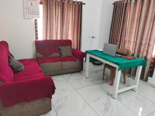 sala de estar con sofá y mesa con ordenador portátil en OYO Abriz Inn, en Elūr