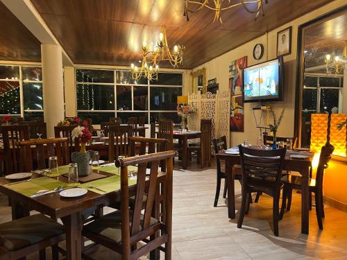 a dining room with tables and chairs and a television at Hill Cool Hotel & Restaurant in Hatton