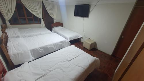 a room with three beds and a television in it at La Chinita hospedaje Cajamarca in Cajamarca