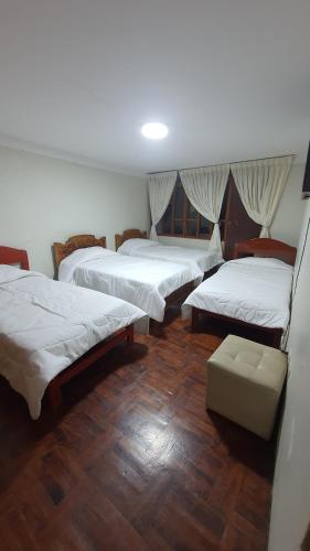 a group of four beds in a room with wooden floors at La Chinita hospedaje Cajamarca in Cajamarca