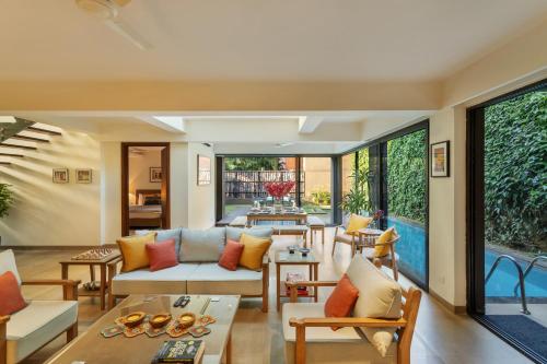 a living room filled with furniture and a large window at Aalia Villas Anjuna, Goa by Aalia Collection in Anjuna
