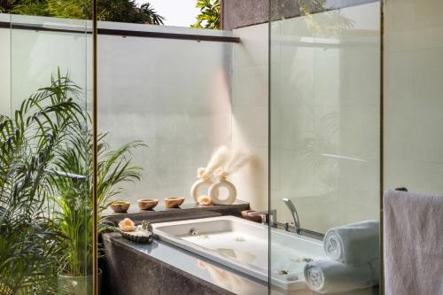 a bathroom with a tub and a glass wall at Aalia Villas Anjuna, Goa by Aalia Collection in Anjuna