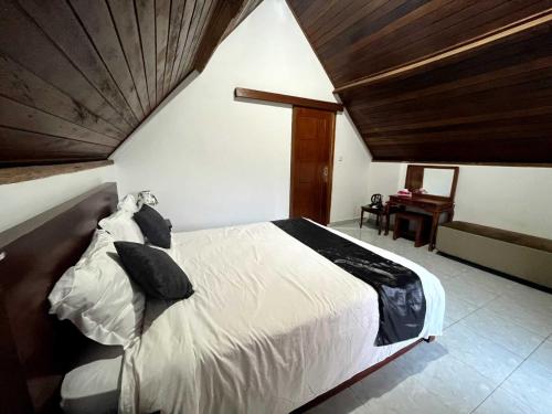 a bedroom with a white bed with a wooden ceiling at Serene Wilderness Villa Batur Natural Hot Spring in Kintamani