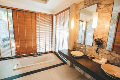 a bathroom with two sinks and a bath tub at Oasis Villa Pattaya in Ban Bung