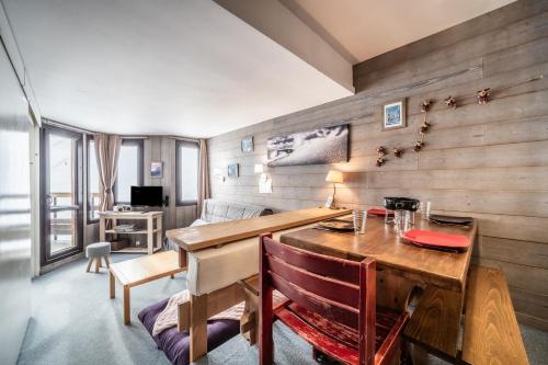 Cette chambre est dotée d'un mur en bois, d'une table et d'un bureau. dans l'établissement Appartement - Pas du lac - Avoriaz, à Avoriaz