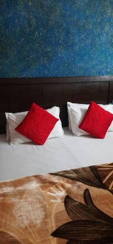 a bed with two red pillows and a painting at Hotel Golden Height in Chandīgarh