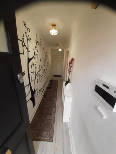 a hallway with white walls with a tree mural on the wall at Lovely and Spacious Room with Conservatory in Gravesend